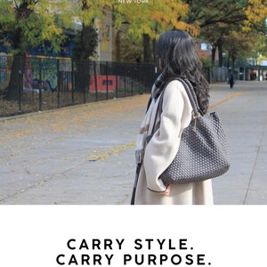 May include: A woman stands outdoors, wearing a light-colored coat and carrying a gray woven tote bag. The bag has a structured shape and a shoulder strap. The text "YNYG NEW YORK" is at the top, and "CARRY STYLE. CARRY PURPOSE. CARRY YNYG." is at the bottom.
