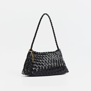 May include: Black woven shoulder bag with a braided handle. The bag features a gold-colored charm and a rectangular shape. The bag is made of a woven material and has a braided handle. The background is plain white.