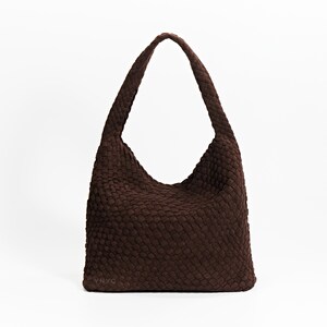 K&ouml;nnte beinhalten: Eine braune Schultertasche mit einem einzelnen Riemen. Die Tasche hat einen rechteckigen Boden und eine abgerundete Oberseite mit einer gewebten Textur. Die Tasche ist aus einem weichen Material gefertigt und f&uuml;r den t&auml;glichen Gebrauch geeignet.