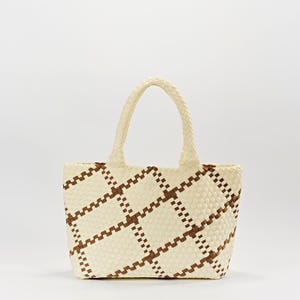 May include: Cream-colored tote bag with a woven design. The bag features a repeating pattern of brown squares and a braided handle. The bag is rectangular with a slightly rounded bottom.