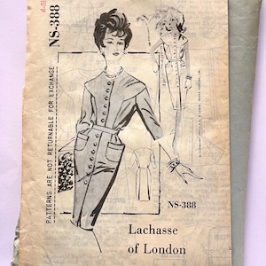 May include: Vintage sewing pattern titled "A Spadea Designer Pattern" by Lachasse of London, size 12. The illustration shows a buttoned front dress with a belted waist. The pattern is in a worn paper envelope with the number NS-388.