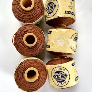 May include: Three spools of brown Clark's O.N.T. mercerized gimp thread, each featuring a cream-colored paper label with blue text. The labels specify 90 yards, color 136 London Tan, and the brand name Clark's Six Cord O.N.T. Gimp.