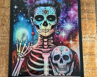 May include: A tarot card with a black background and a colorful illustration of a skeleton with a skull face wearing a flower crown. The card reads "THE IDGAF" in silver lettering.