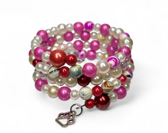 Könnte beinhalten: Ein mehrreihiges Armband aus rosa, weißen und roten Perlen mit einem silbernen Pfotenanhänger.