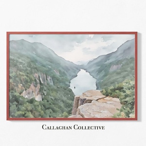 May include: A watercolor painting of a river winding through a valley with lush green mountains on either side. The river is a light blue color and the mountains are a dark green color. The painting is framed in a red frame.