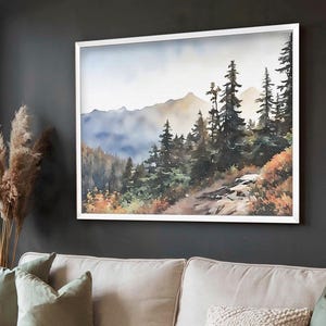 May include: A framed watercolor painting of a mountain landscape. The artwork depicts a forest of evergreen trees, a path, and distant mountains. The color palette includes shades of green, brown, and blue, with a white frame.