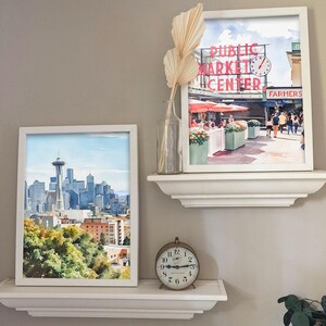 Callaghan Collective Watercolor Painting of Pike Place Market in Seattle Washington featuring the Public Market Center sign, red umbrellas, and the Farmers Market crowd, Pacific Northwest wall art for apartment or office decor.