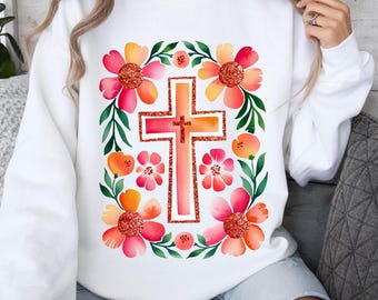 Puede incluir: Sudadera blanca con un diseño floral que presenta una cruz rosa y naranja en el centro. Las flores son rosas, naranjas y amarillas con hojas verdes.