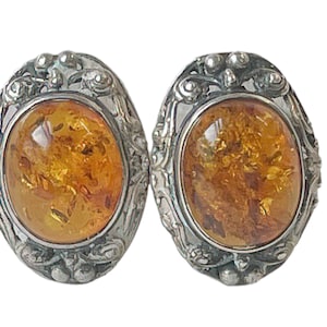 May include: A pair of silver earrings with oval amber stones set in ornate silver frames.