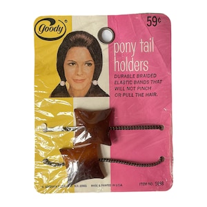 May include: A vintage package of Goody pony tail holders. The package is pink and features a woman with brown hair. The text on the package reads "Goody pony tail holders, Durable braided elastic bands that will not pinch or pull the hair. Item No. 5688".