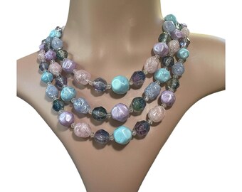 May include: A multi-strand necklace with large, iridescent beads in shades of pink, blue, and purple. The beads are faceted and have a slightly irregular shape.