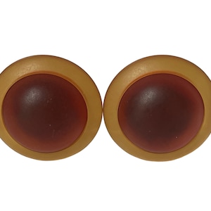 May include: A pair of gold-toned earrings with a round, dark brown center.