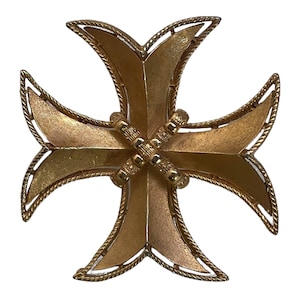 Könnte beinhalten: Eine goldfarbene Brosche aus Metall in Form eines Kreuzes mit filigranen Details. Das Kreuz hat eine strukturierte Oberfläche und eine leicht erhabene Mitte.