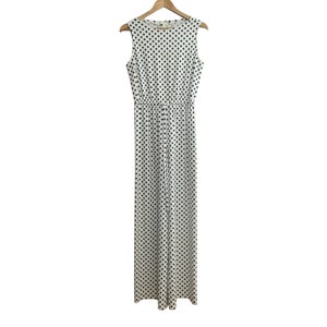 May include: A white sleeveless jumpsuit with a black polka dot pattern. The jumpsuit has a drawstring waist and a relaxed fit.