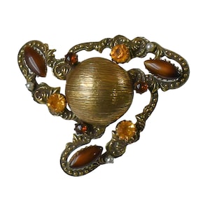 May include: A gold-toned brooch with a large round center stone and smaller stones in various shades of brown and orange.