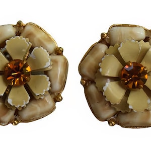 Könnte beinhalten: Ein Paar goldfarbene Ohrclips mit einem Blumendesign, einem hellbraunen Zentrum und einer hellgelben Blume mit einem bernsteinfarbenen Strassstein in der Mitte.