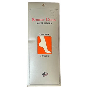 May include: A silver and white package for Bonnie Doon Sheer Liners. The package features a red and white illustration of a foot wearing a sheer liner. The text on the package reads "Bonnie Doon Sheer Liners" and "2 Pair Pack".