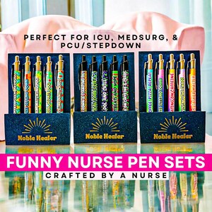 May include: Three sets of pens with humorous phrases for nurses. Each set is in a navy blue box with the words "Noble Healer" and a sunburst design. The pens have colorful designs and gold accents. The text "Funny Nurse Pen Sets" is displayed.