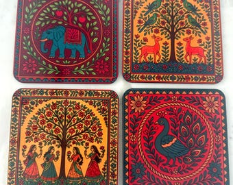 May include: Set of four square coasters with colorful, intricate designs. Each coaster features a different image: an elephant, deer, birds, women, and a peacock, all within floral borders. The coasters have a decorative, artistic style.