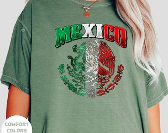 May include: A green t-shirt with the word "MEXICO" in white and red letters and a graphic of the Mexican coat of arms in green, white, and red.