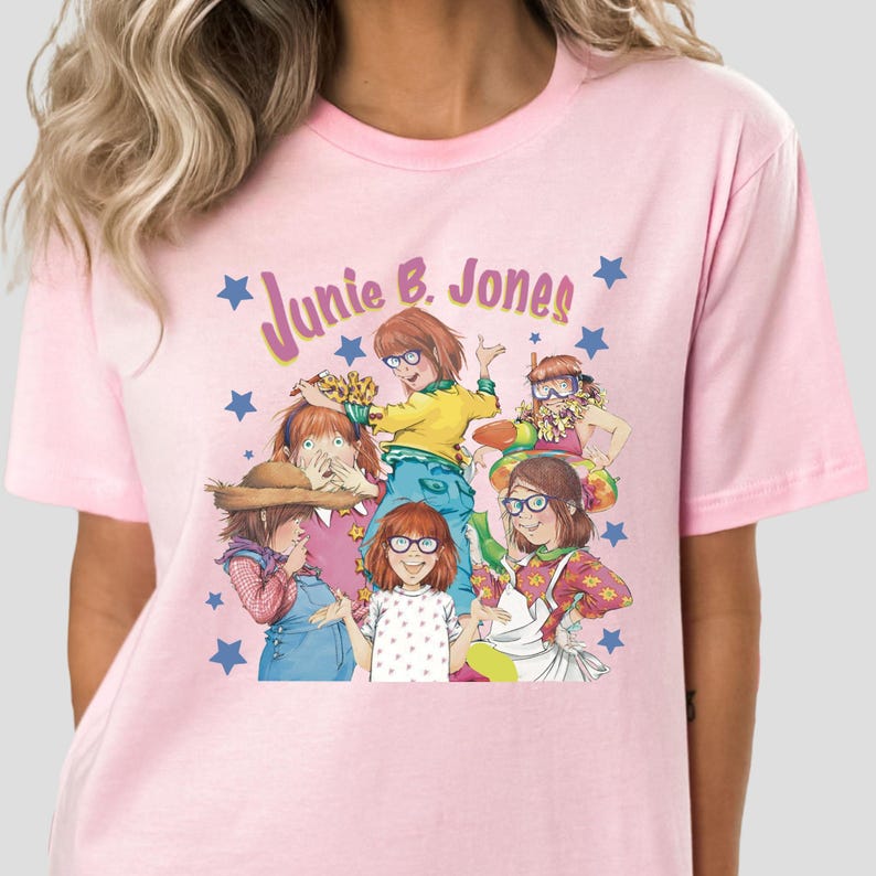 Op de afbeelding: Roze T-shirt met een grafische print van de personages uit de boekenserie "Junie B. Jones". De grafiek bevat de tekst "Junie B. Jones" in een roze en paarse lettertype met sterren.