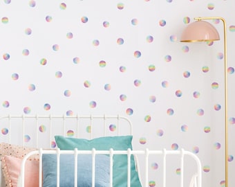 May include: A white metal bed frame with a pink and white patterned comforter and a blue pillow. The wall behind the bed is white with rainbow colored polka dots.