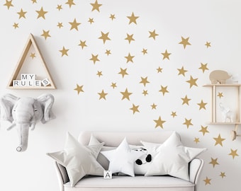 May include: A white couch with two white pillows and one black and white pillow. The wall behind the couch is white with gold star stickers arranged in a diagonal line. The text "MY RULES" is on a shelf above the couch.