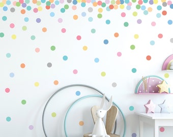 May include: A white wall with colorful polka dot stickers. The stickers are in various shades of pink, blue, green, yellow, and orange. There is a wooden chair with a white rabbit toy sitting on it. The chair is in front of a white wall with colorful polka dot stickers.