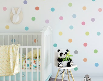May include: A white crib with a yellow and white blanket and a white chair with a panda bear sitting on it. The wall is decorated with colorful polka dots.