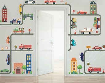 May include: A white wall with a doorway in the center. The wall is decorated with colorful decals of cars, trucks, buildings, and road signs. The decals are arranged in a pattern that resembles a city street.