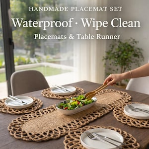 May include: Handmade placemat set with a table runner and four round placemats. The placemats and runner are made of woven natural fiber. The text on the image says "Waterproof • Wipe Clean". White plates with silverware are on the placemats.