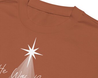 May include: A rust-colored t-shirt with a white star and the text "He Was Born Luke 2" printed on the front.