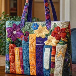 May include: A quilted tote bag featuring a colorful design of stacked books and flowers. The bag has a rectangular shape with a floral pattern on the handles. The books are in various colors, with detailed stitching and floral embellishments.