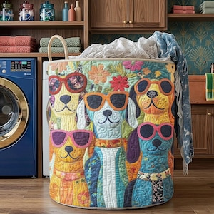 May include: A colorful laundry hamper featuring a whimsical design of dogs wearing sunglasses. The dogs are depicted in various colors, with floral accents and a neutral-toned rim. The hamper has a woven handle and is filled with laundry.