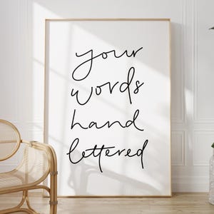 May include: A vertical rectangular wall art print featuring the black handwritten text your words hand lettered on a plain white background, displayed in a thin light wood frame. The design uses a simple cursive script style for the lettering.