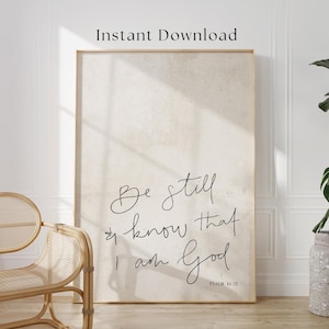 Op de afbeelding: Een ingelijste kunstdruk met de tekst "Be still and know that I am God" in elegant zwart schrift. De achtergrond is een neutraal beige met een subtiel textureffect. De woorden "Instant Download" staan bovenaan.