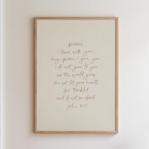 May include: A framed wall art print featuring the text Peace I leave with you; my peace I give you. I do not give to you as the world gives. Do not let your hearts be troubled and do not be afraid. John 14:27 in brown cursive script on a cream background.