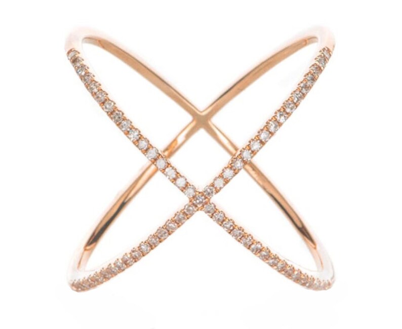 May include: Rose gold criss-cross ring with a double band design. The ring is encrusted with small, sparkling diamonds along the top of each band. The ring is set against a white background.
