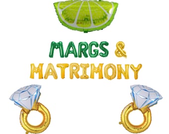 May include: A lime-shaped balloon and text balloons that spell out "MARGS & MATRIMONY". Two diamond ring balloons and an ampersand balloon are also present. The balloons are in green, gold, and white.