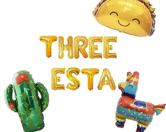 May include: Gold foil balloons spelling "THREE ESTA" with a green cactus, a yellow taco balloon with a smiley face, and a colorful pinata balloon.