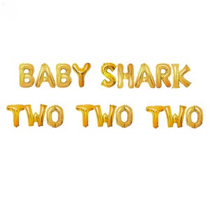 May include: Gold foil letter balloons spelling out "Baby Shark Two Two Two".