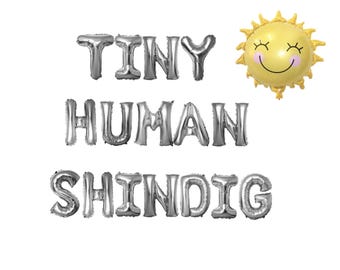May include: Silver foil balloons spelling out "Tiny Human Shindig" with a yellow smiling sun balloon.