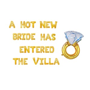 May include: Gold foil balloons spelling "A HOT NEW BRIDE HAS ENTERED THE VILLA" with a diamond ring balloon. The diamond is white and blue, and the ring is gold. Perfect for a bachelorette party or bridal shower.
