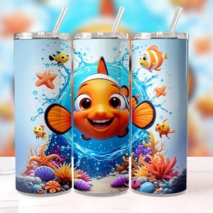 Puede incluir: Tres vasos de acero inoxidable con una vibrante escena submarina con un pez payaso naranja, estrellas de mar y otra vida marina. El diseño incluye salpicaduras de agua y corales coloridos, con una pajita.