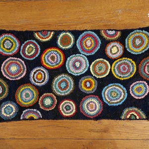 May include: A colorful rug with a dark blue background and a pattern of multi-colored circles. The circles are arranged in a random pattern and are of varying sizes.