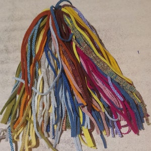 Puede incluir: Un manojo de hebras de hilo de colores en varios tonos de azul, amarillo, rojo, naranja, marrón y blanco.