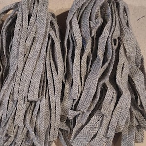 May include: Two bundles of gray and white herringbone trim, each bundle is made up of many long strips of fabric.