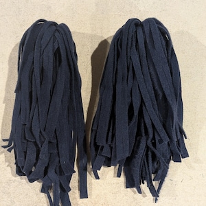 May include: Two bundles of dark navy blue fabric strips, each consisting of multiple long, thin, flat pieces of material gathered together at the top, creating a dense, hanging fringe-like appearance with a uniform matte texture throughout.