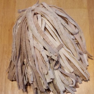 May include: A pile of beige and white yarn strands, resembling a mop head.