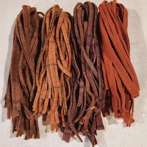 May include: Four bundles of brown, orange, and purple wool yarn with a frayed texture. The yarn is perfect for crafting projects like rugs, wall hangings, and other home decor.
